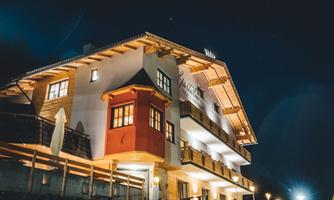 A modern building with a traditional style, illuminated at night. It features a charming bay window and an inviting terrace.