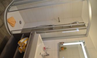 A modern bathroom with a shower and a sink. Towels are neatly stacked on a shelf.