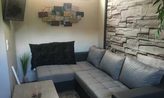 A modern living room with a gray couch and a coffee table. On the wall, decorative elements and a plant can be seen.