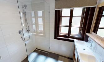 A modern bathroom with a walk-in shower and a large window. The space is bright and designed in a minimalist style.