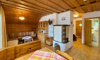 A cozy living space with wooden walls and furniture. There is a sofa, a table, and a fireplace in the corner.