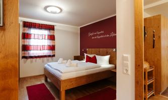A cozy bedroom with a double bed. The walls are painted in warm colors, and a large window lets in natural light.