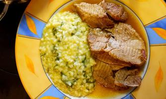 A plate with tender meat and green risotto. The colorful serving dish gives the dish an appealing presentation.