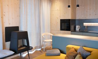Modern kitchen with light wood walls and elegant furnishings. A cozy sofa and a small dining table invite you to linger.