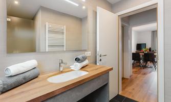 A modern bathroom with a sink made of concrete and wood. Towels are neatly folded on the shelf.