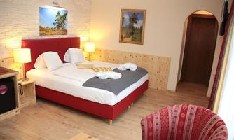 A cozy bedroom with a large bed and warm colors. The furnishings include an armchair and a window that brightens the room.