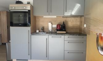 A modern, gray kitchen with appliances. The kitchen unit is compact and well-equipped.