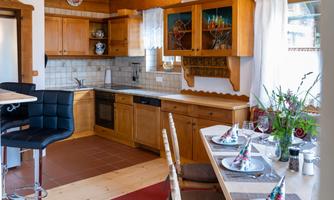 A bright kitchen with wooden cabinets and modern appliances. The table is set with care, featuring flowers and decorations.
