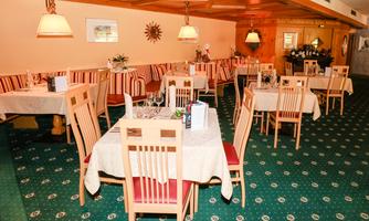 A cozy restaurant with tables and chairs in beige and red design. The decor is warm and inviting, suitable for a relaxed meal.
