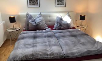 A bedroom with a large bed decorated with striped bedspreads and pillows. Next to the bed are nightstands with lamps.