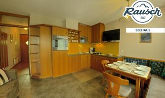 A cozy kitchen area with wooden cabinets and a dining table. The furnishings are functional and inviting.