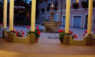 A beautiful courtyard with a fountain in the center. Flowers in pots and gentle lighting create an inviting atmosphere.