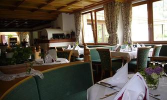 An inviting restaurant with elegant tables and green upholstery. Bright windows let in plenty of natural light, while decorative curtains make the space cozy.