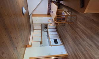 A bright and cozy apartment with wooden ceilings. The open kitchen has a dining area and a television.