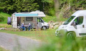 A RV camping site in nature. Two people enjoy the tranquility outdoors.