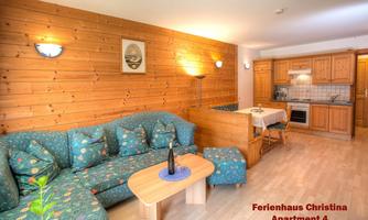 A modern apartment with wooden paneling and a cozy seating area. The kitchen is well-equipped and invites cooking.
