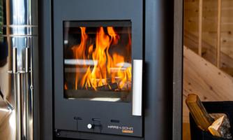 A modern stove with a flaming fire. The stove is situated in a stylish interior made of wood.