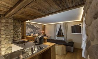 A cozy accommodation with wooden details and stone walls. The kitchen is modern and well-equipped, with a window that lets in natural light.