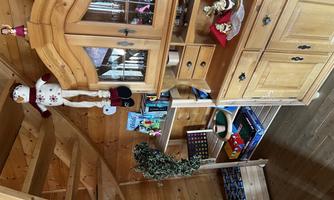 A cozy room with wooden shelves and a beautiful wooden cabinet. There are decorative items and games on the shelves.