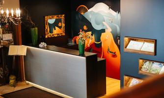 A reception area with a modern reception desk and colorful wall design. On the wall, illustrations of landscapes and figures can be seen.