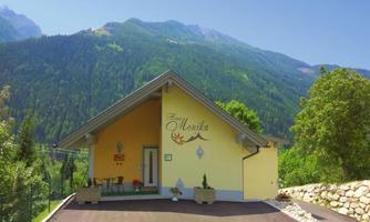 A charming yellow house surrounded by green mountains. The entrance is inviting and well-designed.