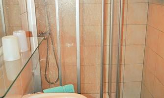 A small bathroom with a shower cubicle and a sink. The walls are tiled and there are towels in turquoise.