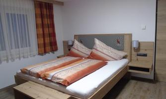 A cozy bedroom with a large bed and decorative pillows. The warm colors of the bedding and curtains create an inviting atmosphere.