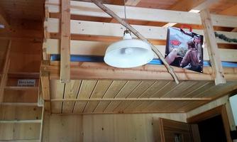 A cozy wooden house with an open sleeping loft. A lamp and a cozy atmosphere define the space.