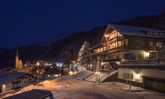 A picturesque village in winter at night, illuminated by warm lights. Snow-covered houses and a tranquil atmosphere create a cozy ambiance.