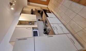 A modern kitchen with bright cabinets and a microwave. The floor is tiled, and there is access to the door on the right side.