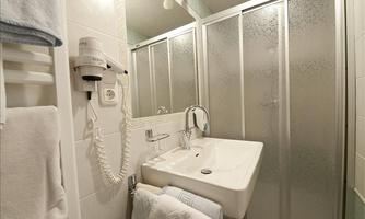 A modern bathroom with a sink and a shower cubicle. Towels are neatly hung on a towel rack.