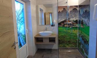 A modern bathroom with a shower and a sink. The walls are decorated with a beautiful landscape graphic.