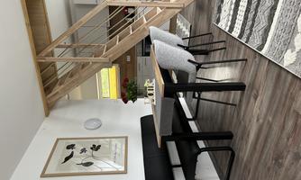 A modern dining room with a table and five chairs. A bright wooden staircase leads to an upper floor.
