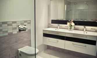 A modern bathroom with a stylish shower enclosure, a white toilet, and a spacious sink with a mirror. The walls are tiled in soft colors and a flower vase adds a fresh accent to the room.