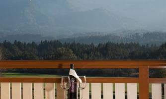 An elegant table with chairs on a balcony. Majestic mountains rise in the background beneath a clear sky.