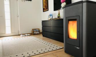 A cozy room with a modern stove that emits warm light. In the background, a rug, a sideboard, and a brightly lit door are visible.