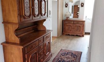 A bright hallway with antique wooden furniture and a tasteful carpet. The walls are light, and the light is illuminated by elegant lamps.