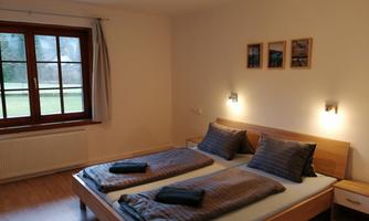 A cozy bedroom with a double bed and two nightstands. Large windows let in plenty of light and offer a view of the greenery.