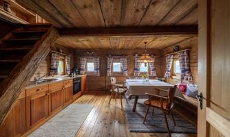 A cozy kitchen with wood paneling and rustic furniture. Large windows provide plenty of daylight and an inviting atmosphere.