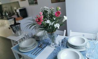 A beautifully set table with several plates, cutlery, and glasses. In the center stands a vase with colorful flowers.