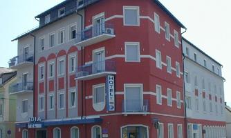 A multi-story hotel building in bright red and white. It has balconies and features an inviting entrance.