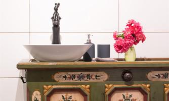 A decorative sink on an artistically painted cabinet. Fresh flowers in a vase give the room an inviting atmosphere.