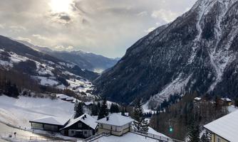An idyllic mountain landscape in the snow with several cabins. The clouds drift across the sky, and the mountains are majestic.