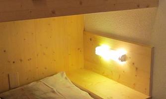 A cozy family room with a wooden bunk bed. Soft lighting creates a pleasant atmosphere.