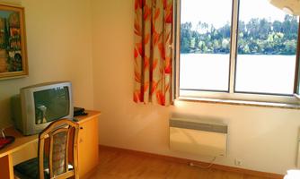 A simple room with wooden floor and a desk. A beautiful view of nature is visible through the window.