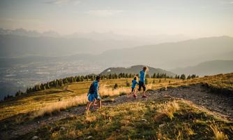 A group of children is hiking up a hill. In the background, mountains and a beautiful view of the valley can be seen.