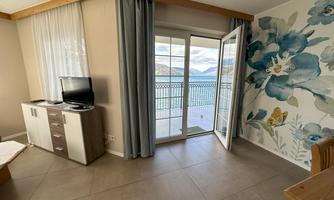 A bright room with large windows and a view of the water. On the wall, there is a colorful floral motif.