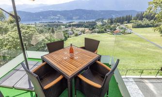 A beautiful view from a terrace with a table and four chairs. In the background, green meadows and mountains can be seen.