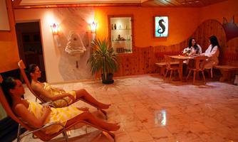 A wellness area with relaxing loungers and a cozy ambiance. Two women enjoy their time at the table, while another rests on a lounger.