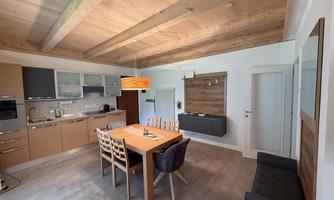 A modern kitchen with a dining area and a large table.  
Bright wooden ceilings and a cozy atmosphere create an inviting space.